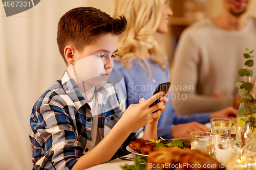 Image of boy with smartphone at family dinner party