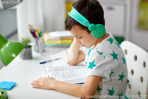 Image of boy in headphones with textbook learning at home