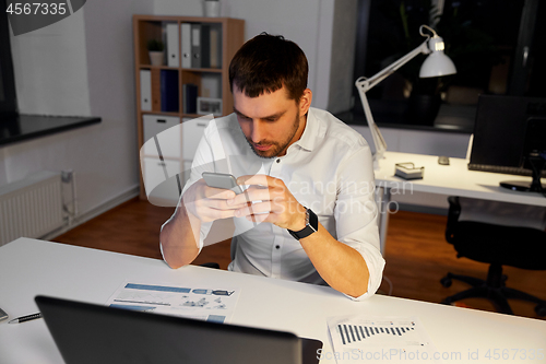 Image of businessman with smartphone and computer at office