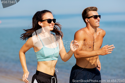 Image of couple with earphones running along on beach
