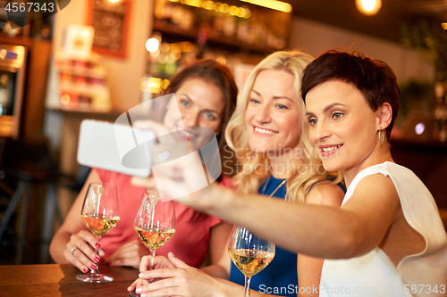 Image of women taking selfie by smartphone at wine bar