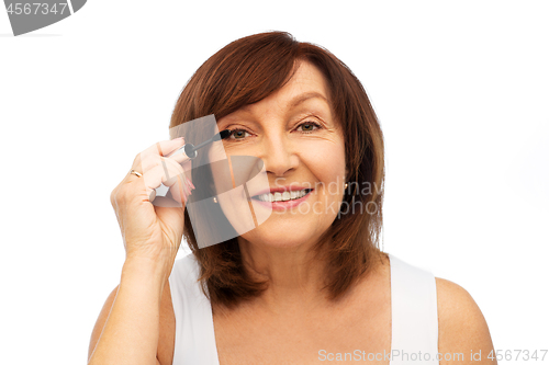 Image of smiling senior woman applying mascara to eyelashes