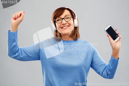 Image of senior woman in headphones listening music on cell