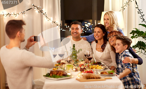 Image of family having dinner party and taking selfie