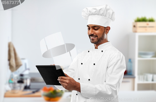 Image of happy indian chef with tablet computer at kitchen