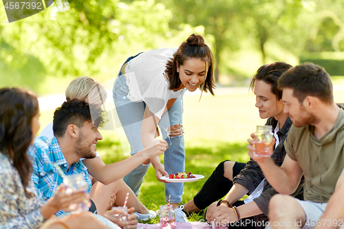 Image of friends with drinks and food at picnic in park