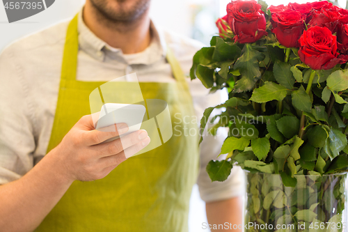 Image of florist with smartphone and roses at flower shop