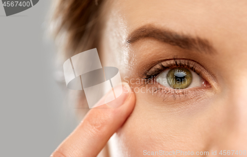 Image of close up of woman pointin finger to eye