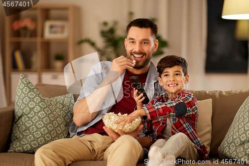 Image of happy father and son watching tv at home