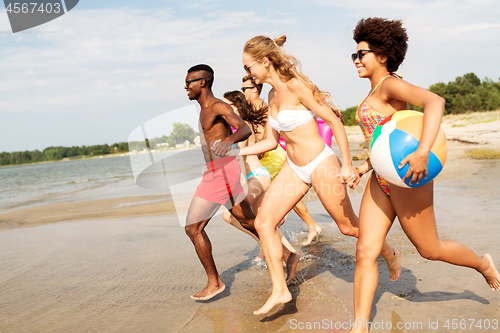 Image of friends run with beach ball and swimming mattress