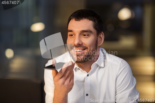 Image of businessman recording voice message on smartphone