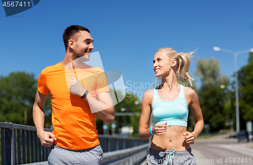 Image of couple with fitness trackers running along bridge