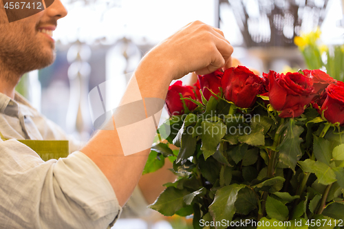 Image of florist or seller setting red roses at flower shop