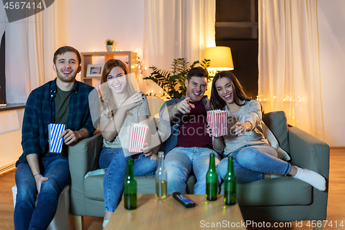 Image of friends with beer and popcorn watching tv at home