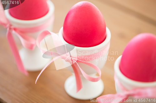 Image of pink colored easter eggs in holders on table