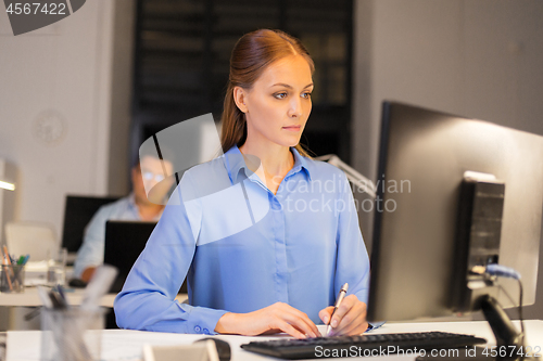 Image of businesswoman at computer working at night office