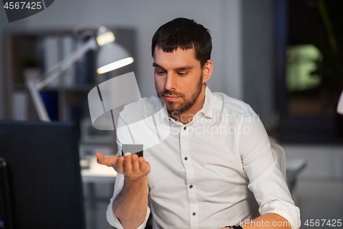 Image of businessman using smart speaker at night office