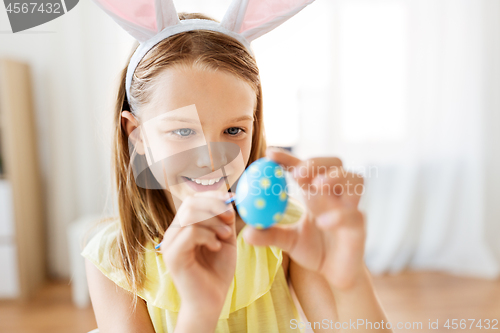 Image of happy girl coloring easter eggs at home