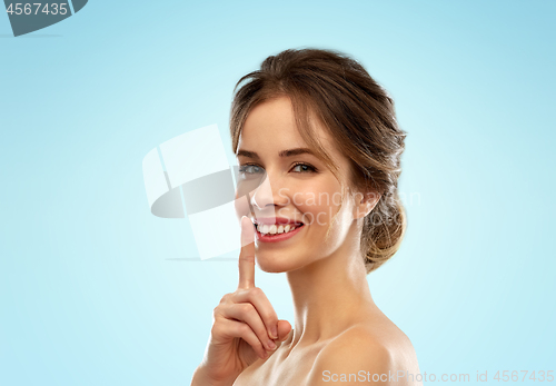 Image of beautiful smiling woman making hush gesture