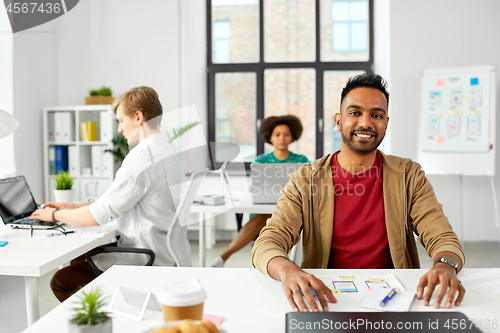 Image of indian male creative worker with laptop at office