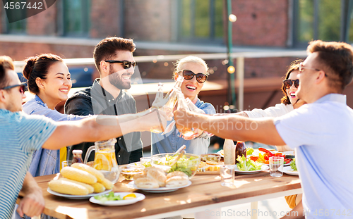 Image of happy friends toasting drinks at rooftop party