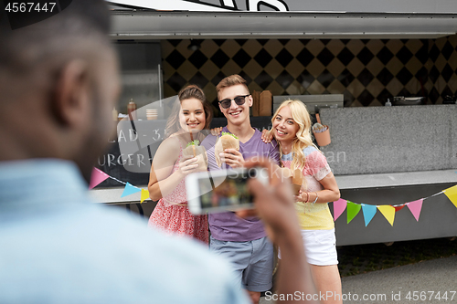 Image of man taking picture of friends eating at food truck