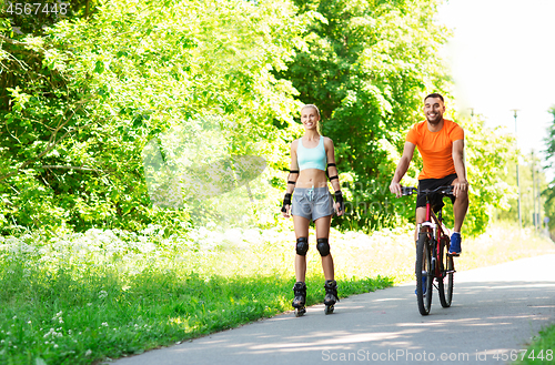 Image of happy couple with rollerblades and bicycle riding