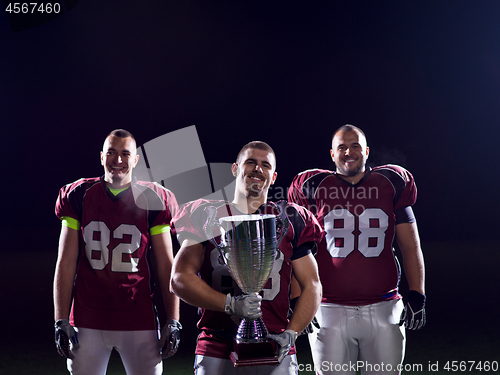 Image of american football team with trophy celebrating victory