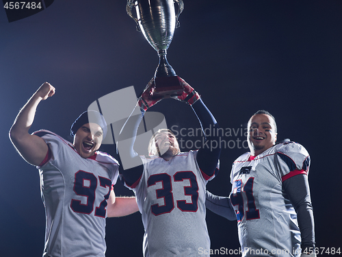 Image of american football team with trophy celebrating victory