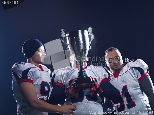 Image of american football team with trophy celebrating victory