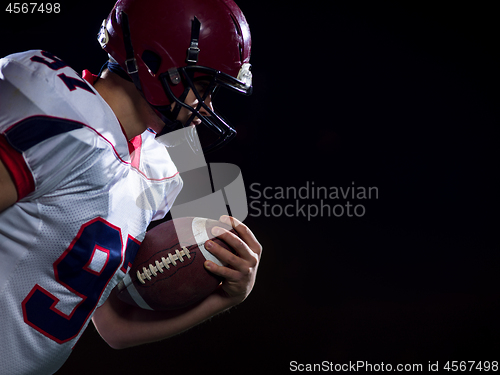 Image of American football player holding ball while running on field