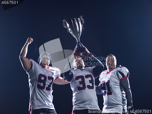 Image of american football team with trophy celebrating victory