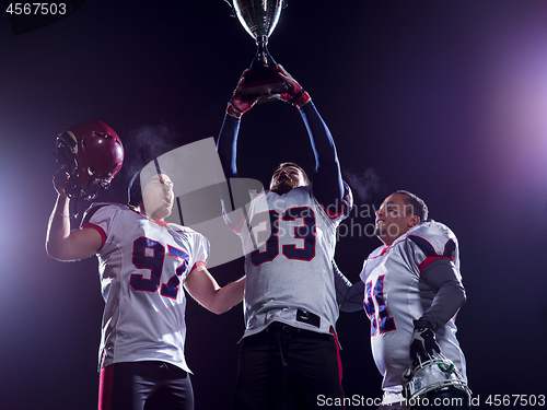 Image of american football team with trophy celebrating victory