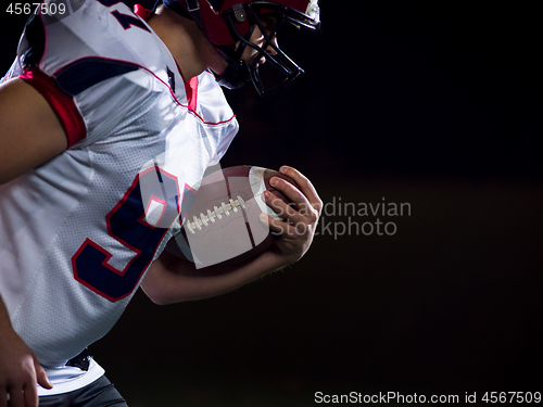 Image of American football player holding ball while running on field