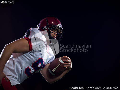 Image of American football player holding ball while running on field