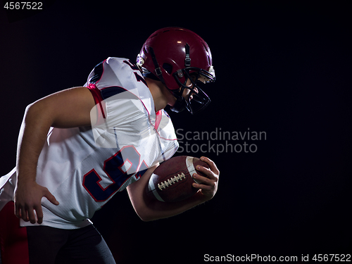 Image of American football player holding ball while running on field