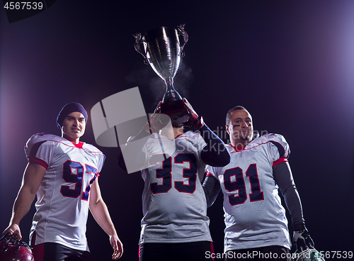 Image of american football team with trophy celebrating victory