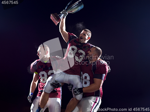 Image of american football team with trophy celebrating victory