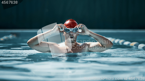 Image of fit swimmer in cap at pool