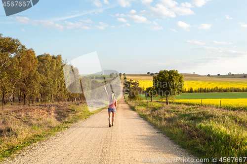 Image of Woman walking along a dusty road among the rural fields