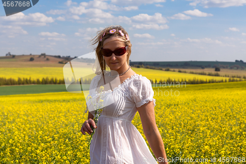 Image of Female  by a field of flowering canola and rolling hills