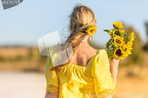 Image of Female holding bunch of beautiful sunflowers in rural landscape