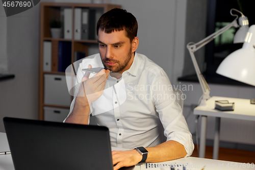 Image of businessman recording voice message on smartphone