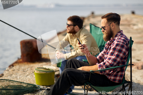 Image of friends with smartphone and beer fishing on pier