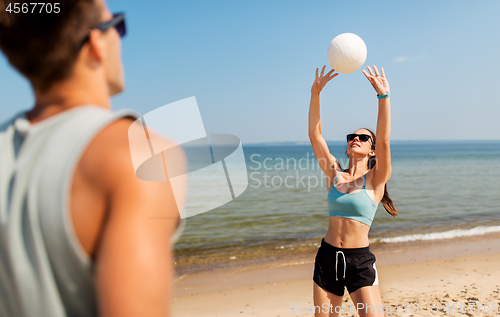 Image of happy couple playing volleyball on summer beach