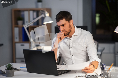 Image of businessman with laptop working at night office