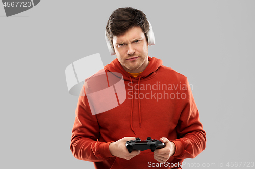 Image of displeased man with gamepad playing video game