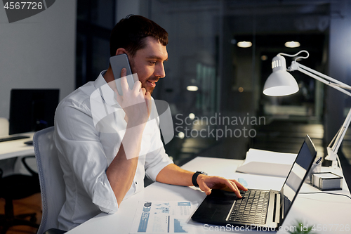 Image of businessman calling on smartphone at night office