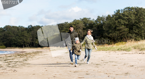 Image of happy family running along autumn beach