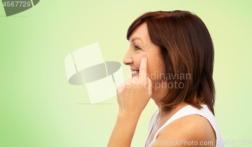 Image of profile of senior woman pointing to eye wrinkles